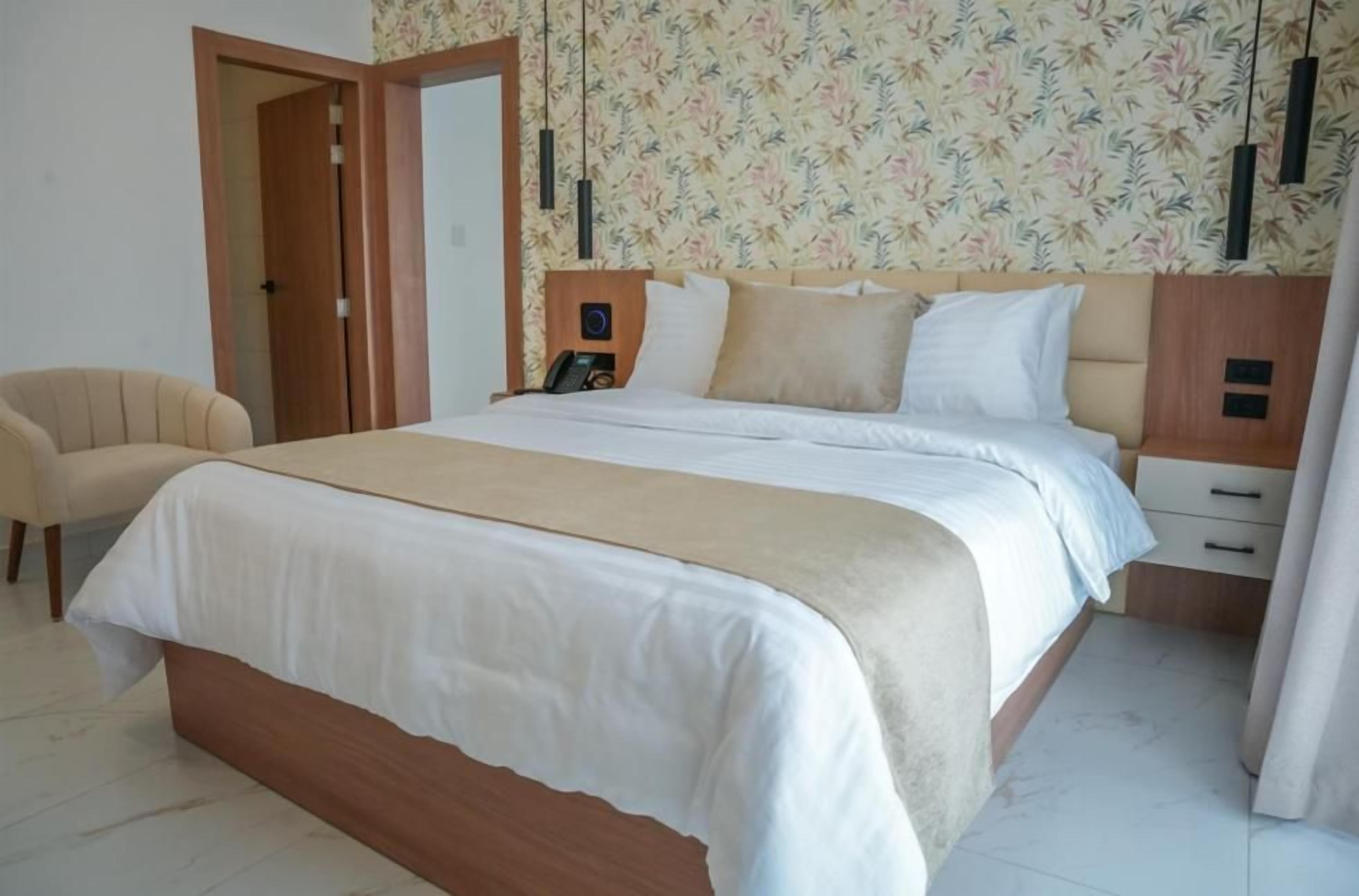 A bedroom with a bed, bedside tables, a chair, and a door.