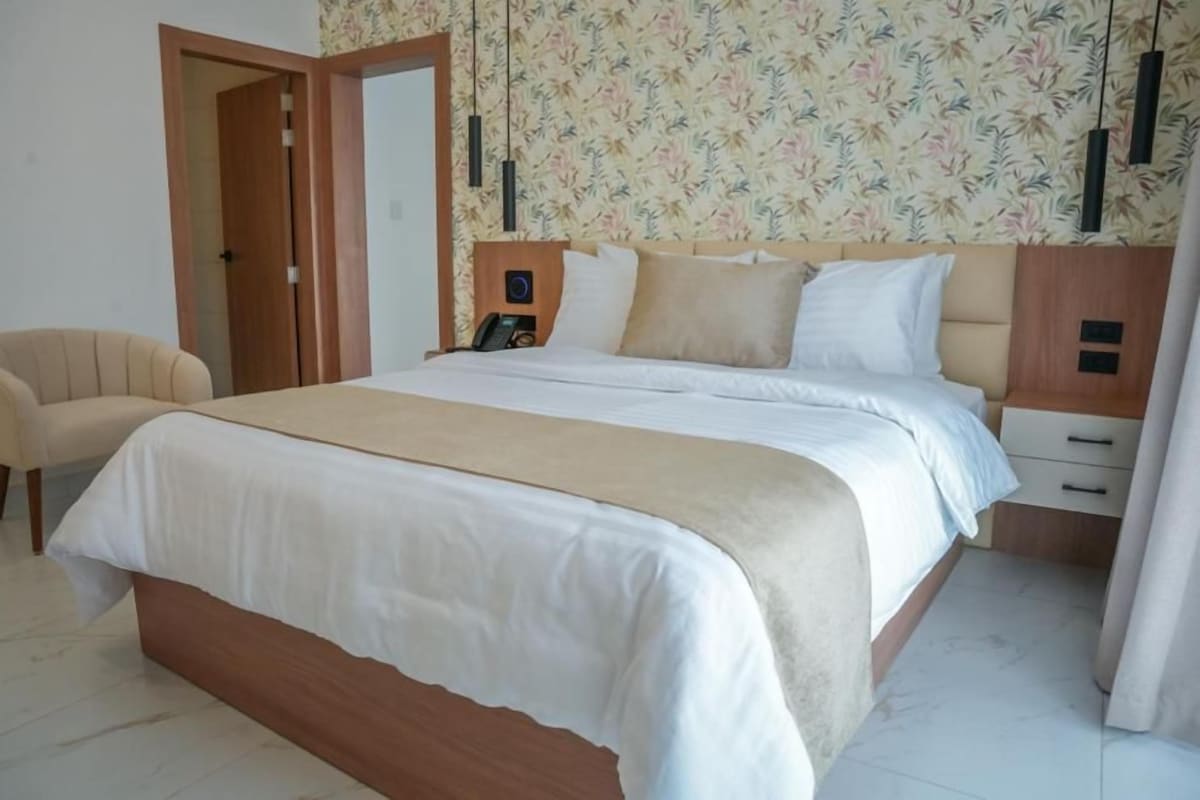 A bedroom with a bed, bedside tables, a chair, and a door.