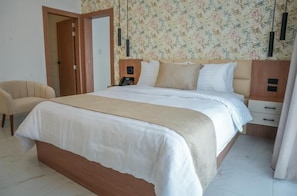 A bedroom with a bed, bedside tables, a chair, and a door.