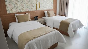 A hotel room with two beds, a wooden headboard, a nightstand, and a floral-patterned wall.