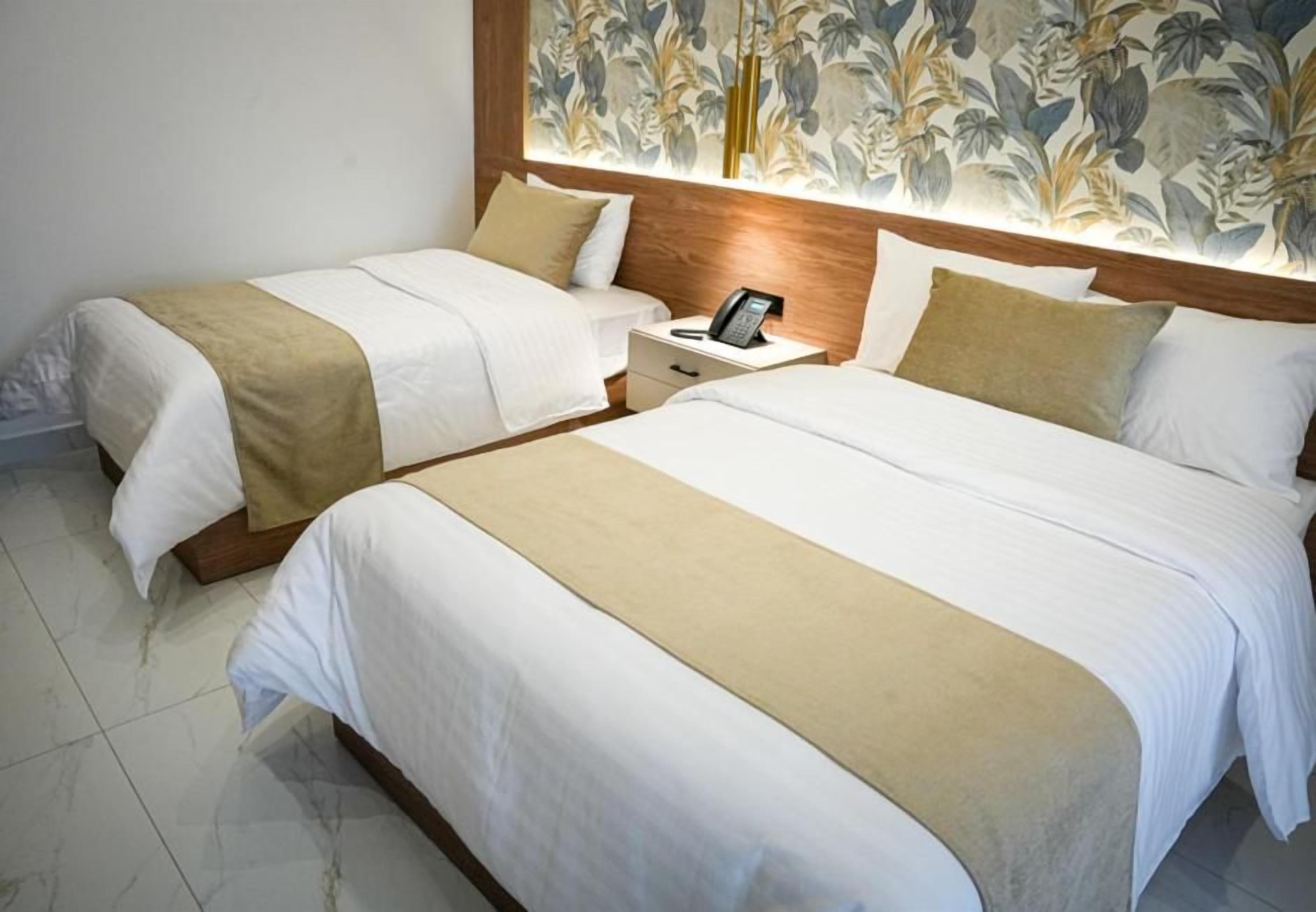 Hotellihuone, jossa on kaksi sänkyä, yöpöytä ja puhelin.