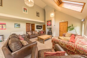 A spacious living room with leather sofas, a wooden coffee table, and a fireplace.