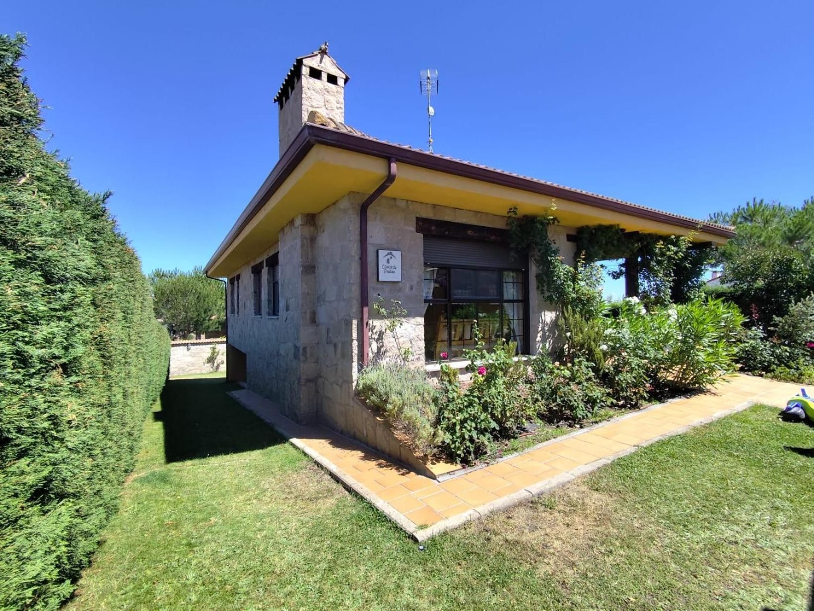 Un petit bâtiment en pierre avec un toit jaune, une cheminée et une enseigne indiquant qu’il s’agit d’une maison d’hôtes.