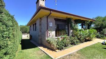Un petit bâtiment en pierre avec un toit jaune, une cheminée et une enseigne indiquant qu’il s’agit d’une maison d’hôtes.