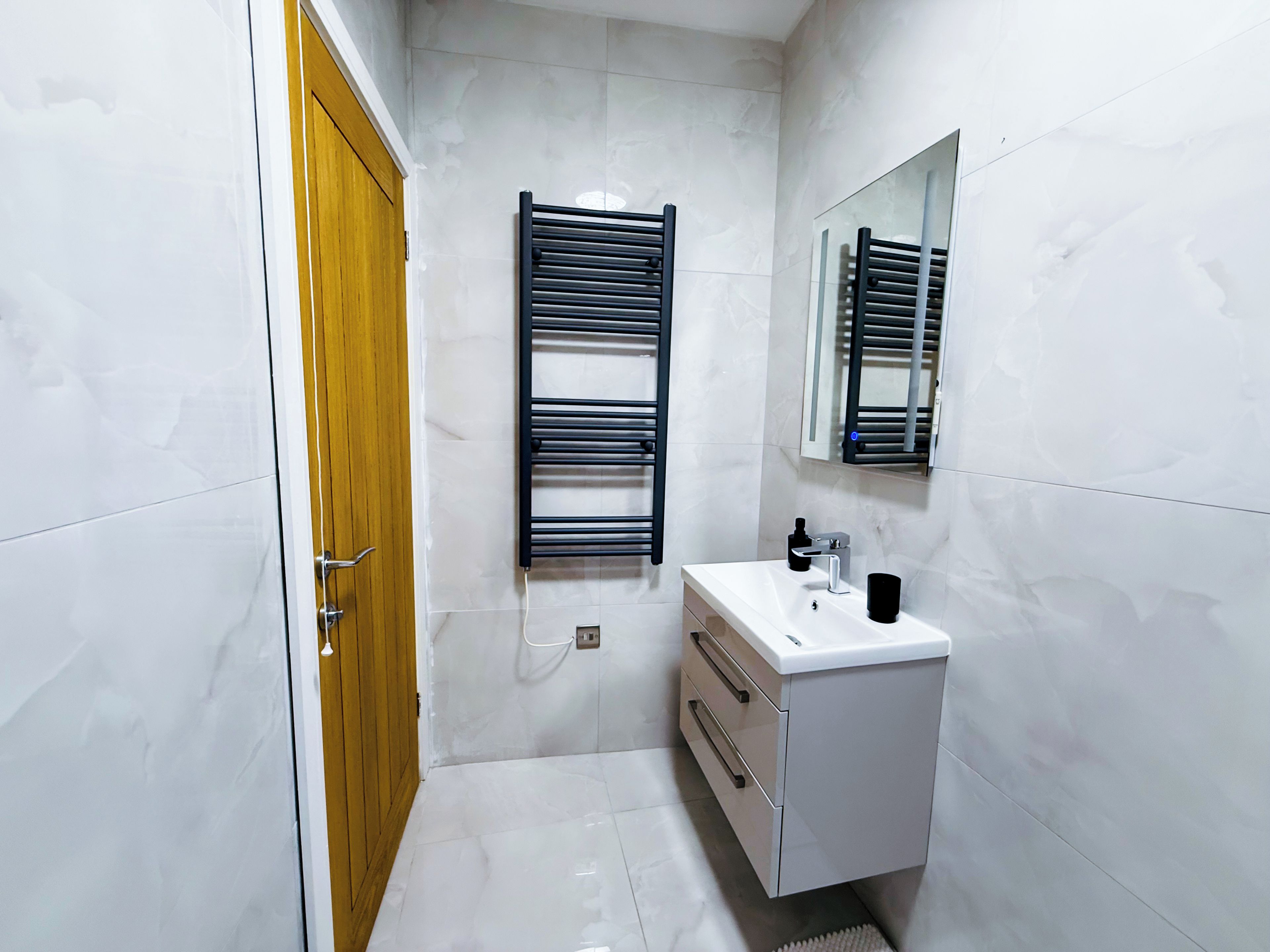Une salle de bain avec un meuble-lavabo blanc, un porte-serviettes et une porte en bois.