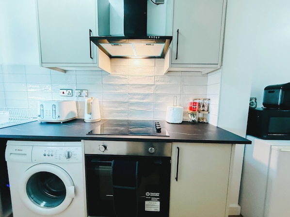 A compact kitchen with a Bosch washing machine, a toaster, and a coffee maker on the counter.