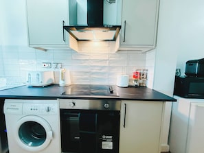 A compact kitchen with a Bosch washing machine, a toaster, and a coffee maker on the counter.