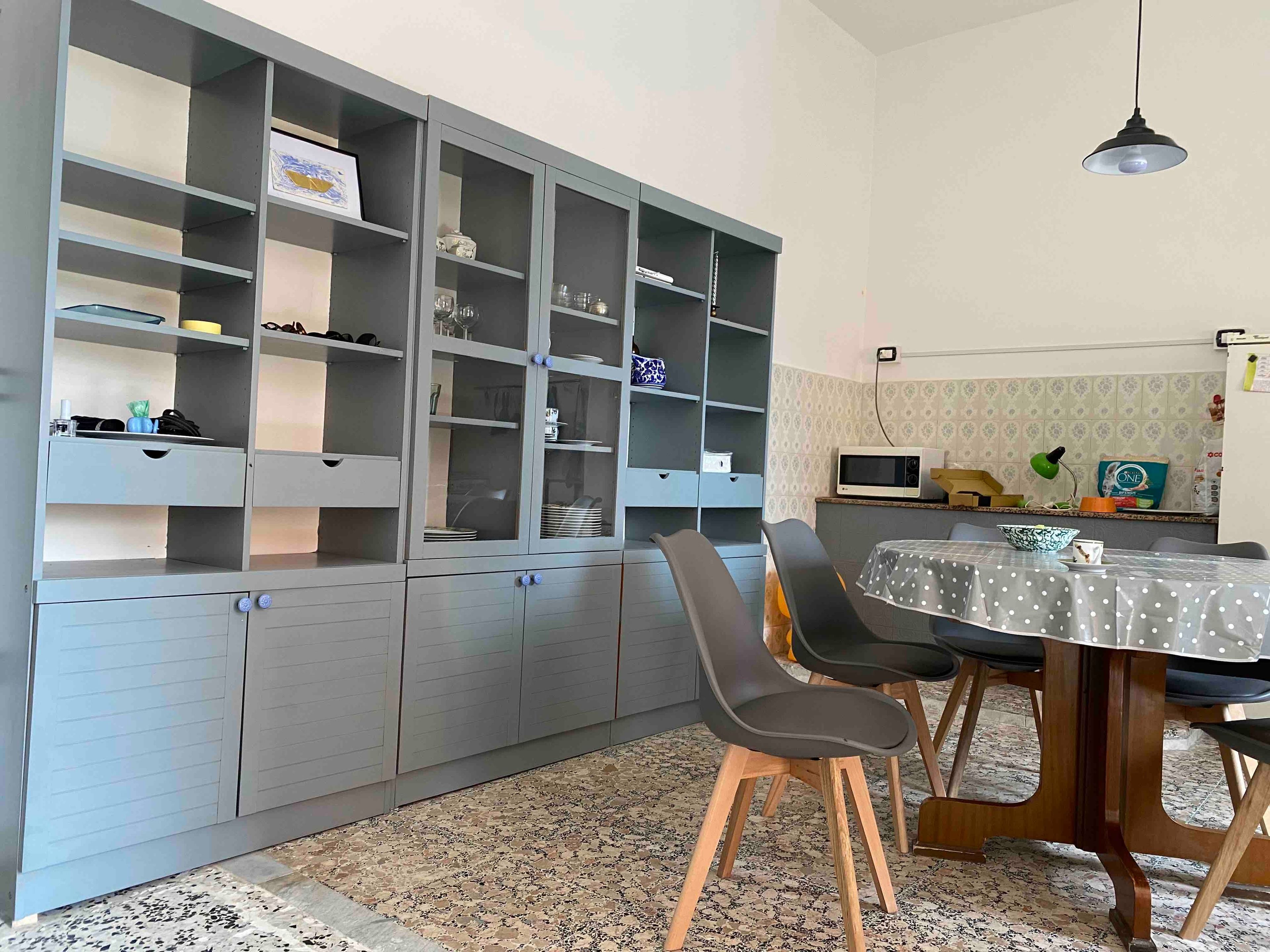 A dining area with a table, chairs, and a cabinet with open shelves.