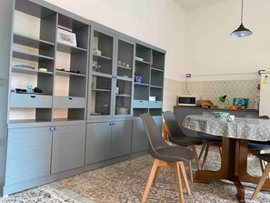 Un espace repas comprenant une table, des chaises et un meuble avec des étagères ouvertes.