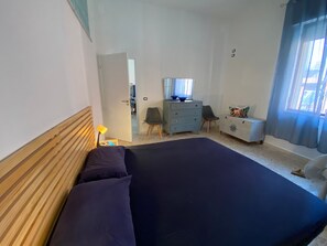 A bedroom with a large bed, a dresser, a chair, and a desk.