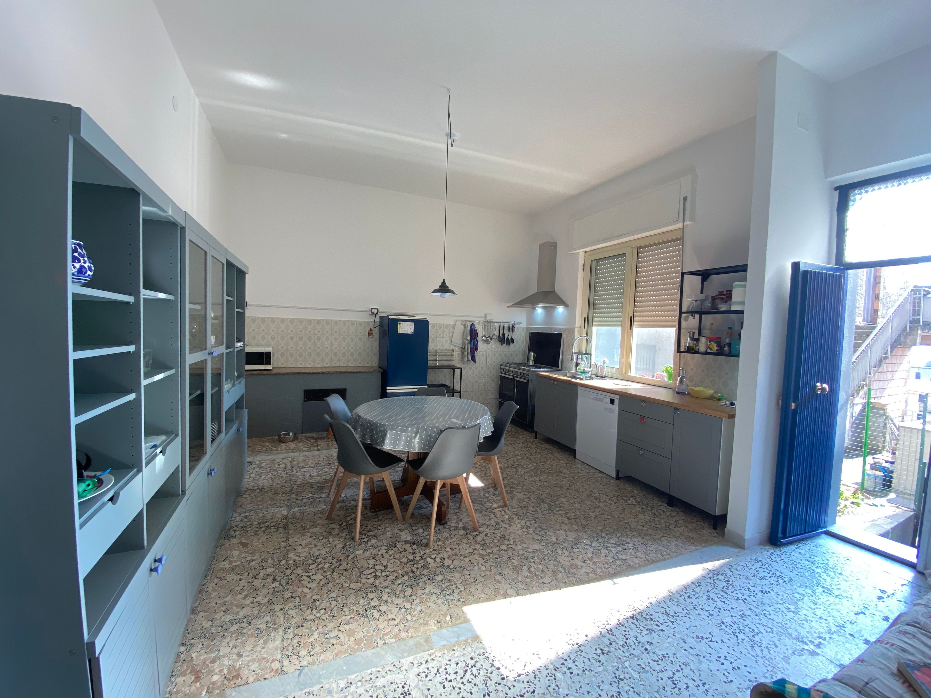 Een kleine keuken met een eettafel, kastjes en een raam.