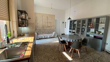 Eine kompakte Küche mit Spüle, einem Esstisch mit Stühlen, einer Couch und einem Schrank mit Glastüren.