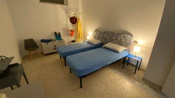 Une chambre avec deux lits, un bureau, une chaise, une armoire et une fenêtre.