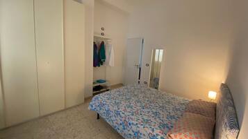 Ein Schlafzimmer mit Bett, Kleiderschrank, Spiegel und Tür.