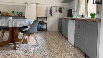 A kitchen with a dining table, chairs, a stove, and a sink.