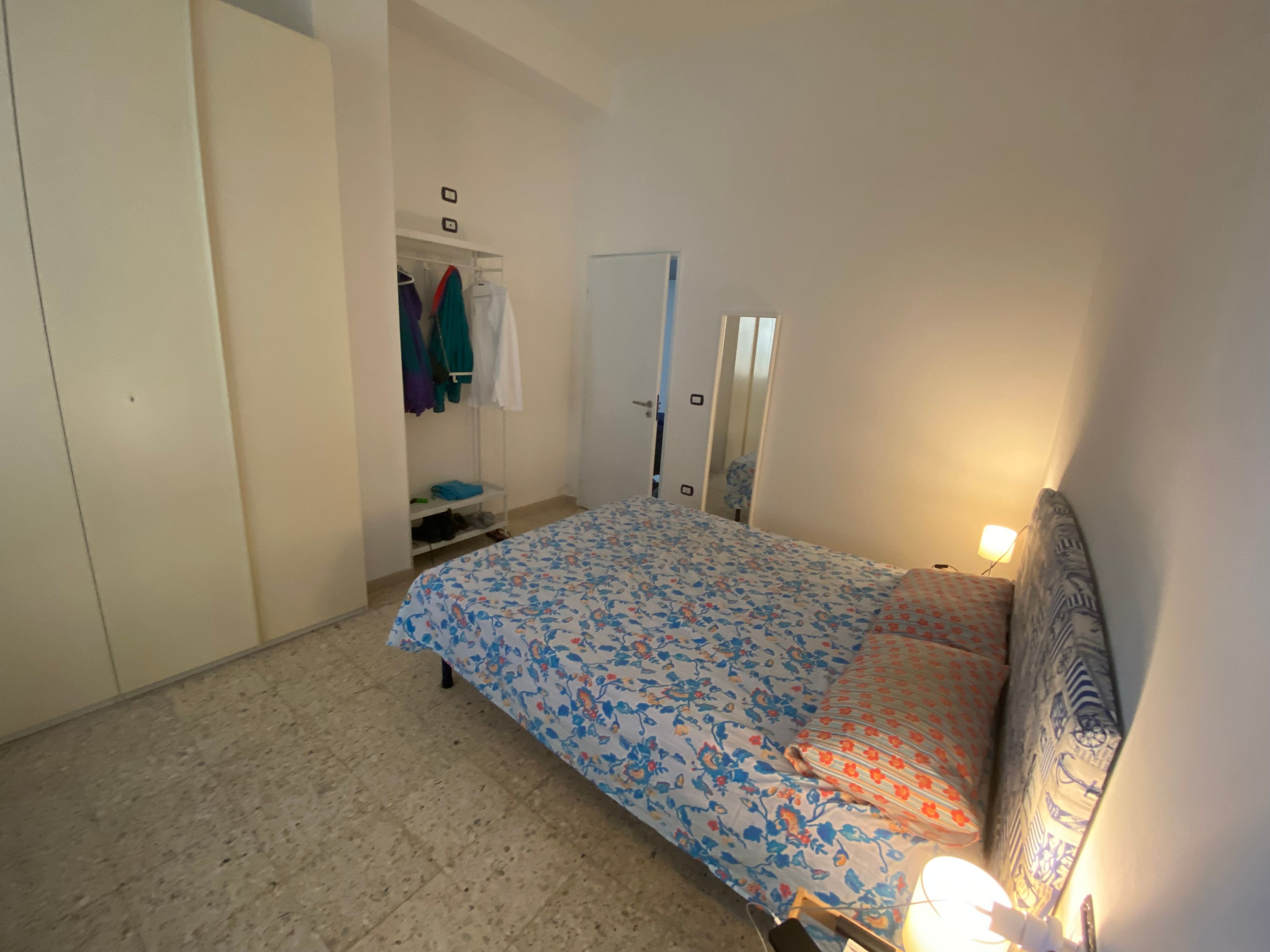 Een slaapkamer met een bed, een kledingkast, een spiegel en een deur.