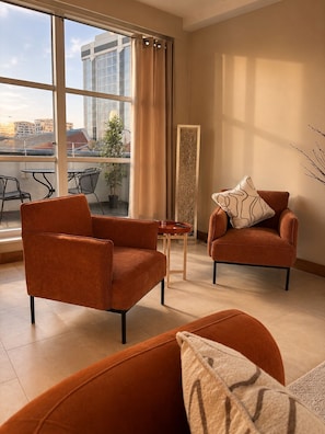 Una sala moderna con dos sillones naranjas, una mesita y un panel decorativo.