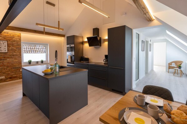 A modern kitchen with a central island, built-in appliances, and a dining area with breakfast items.
