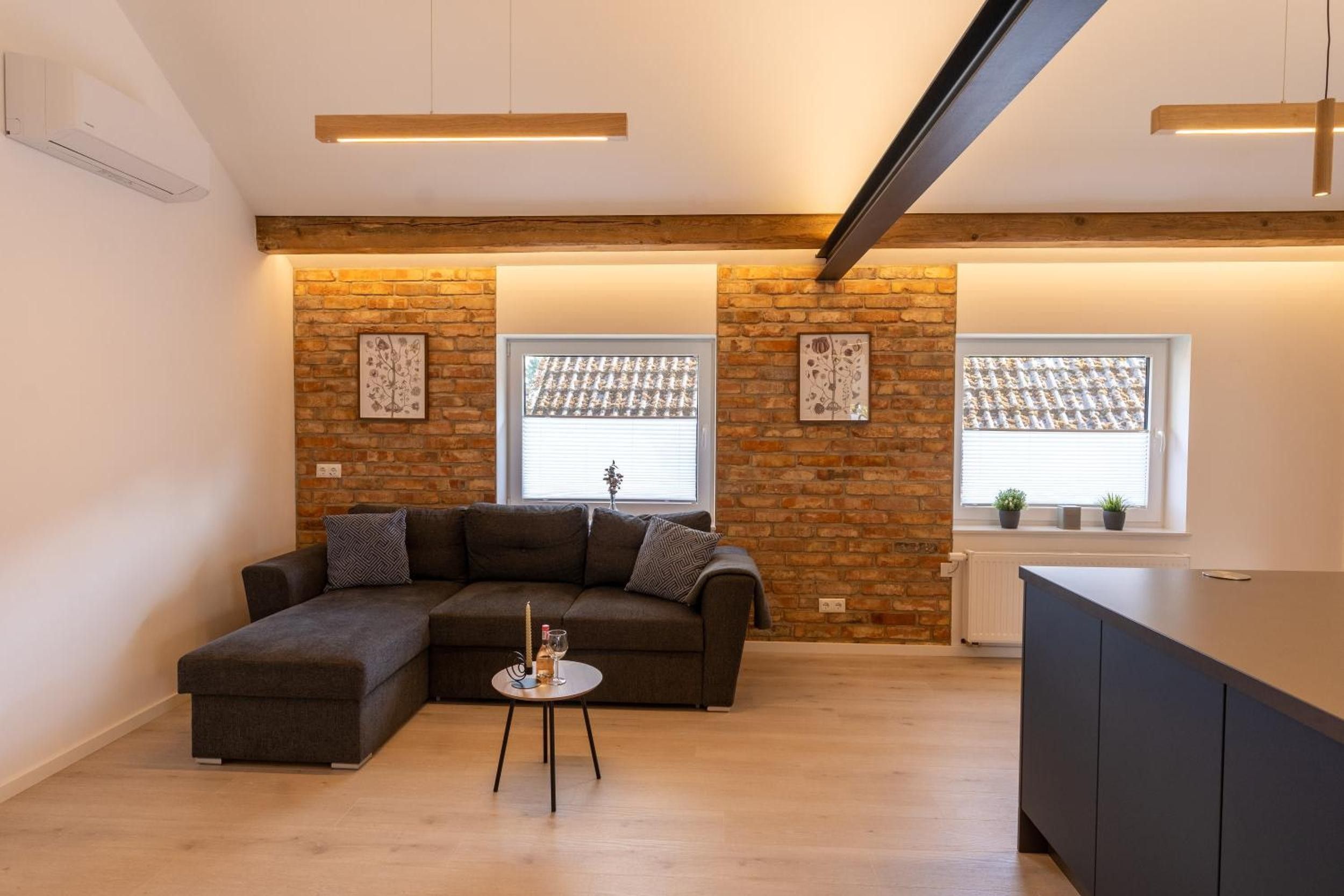 Un espacio habitable moderno con un sofá modular, una mesita redonda y una zona de cocina.