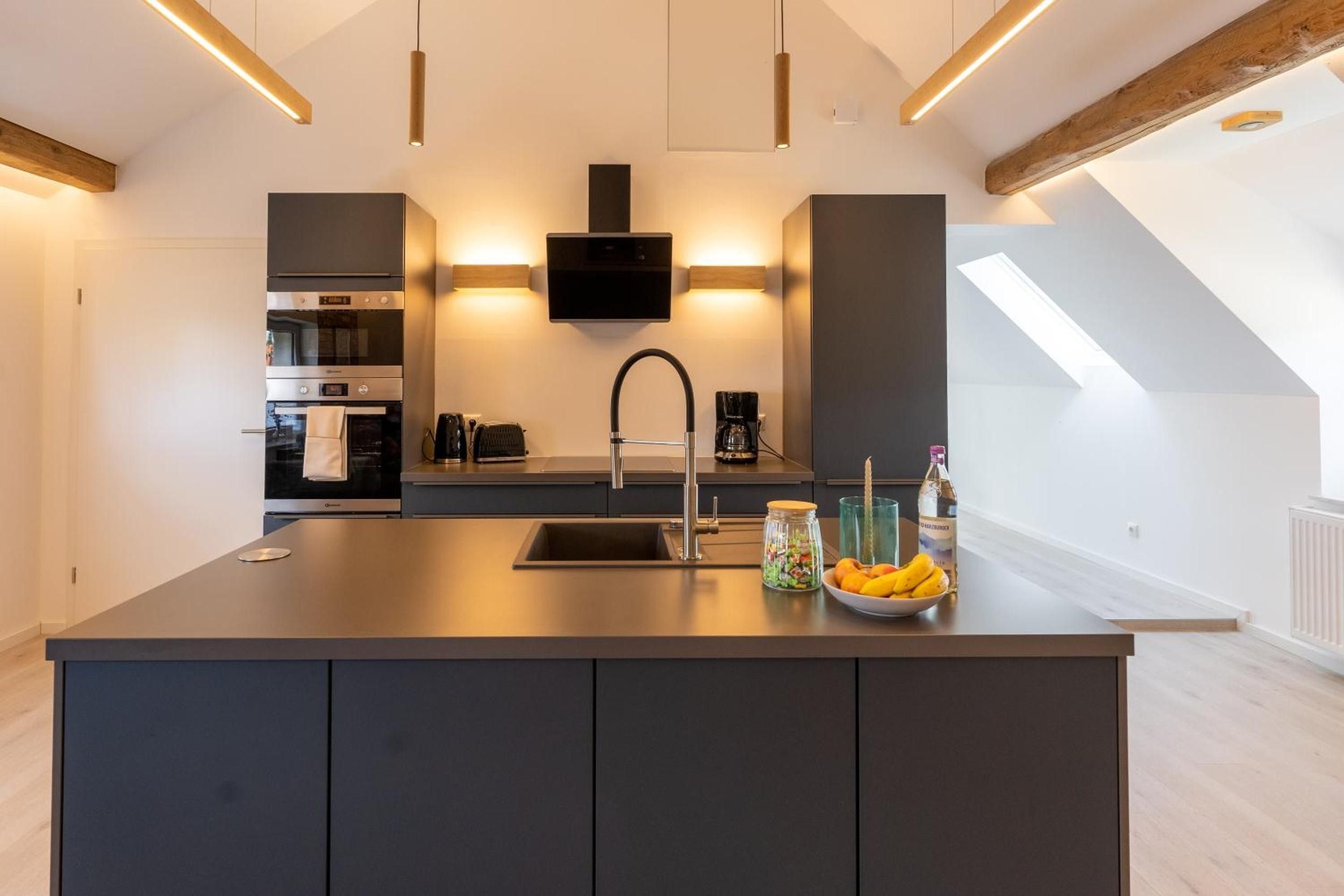 Una cocina moderna con una isla central, electrodomésticos integrados y un ventanal grande.