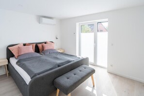 Un dormitorio moderno con cama, mesitas de noche y un banco.