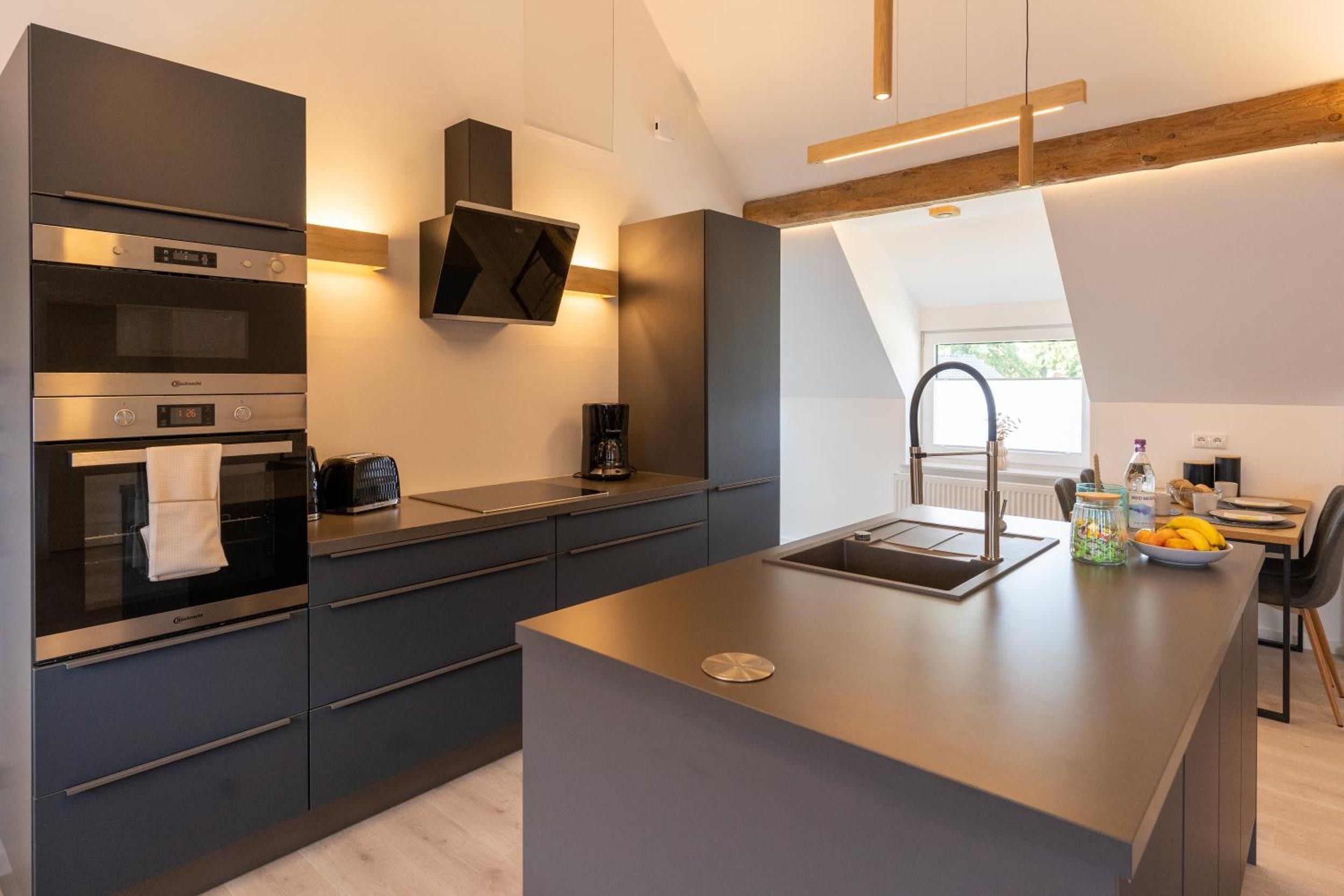 A modern kitchen with built-in appliances, a central island, and a view of the outdoors.
