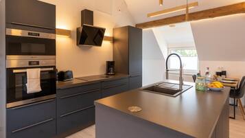 A modern kitchen with built-in appliances, a central island, and a view of the outdoors.