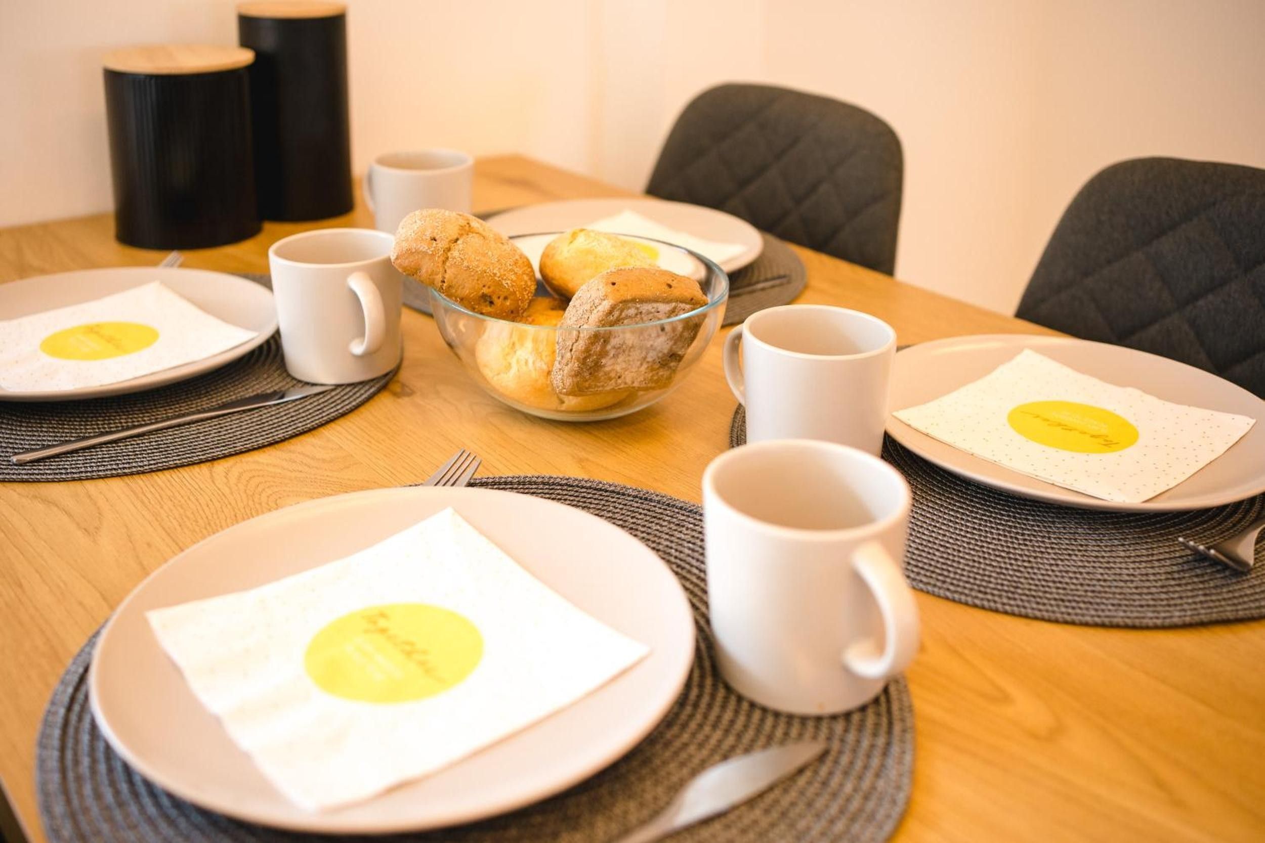 Una mesa de comedor dispuesta con platos, tazones y tazas, con una vista despejada del centro de la mesa.