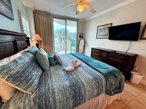 Ein Schlafzimmer mit einem Bett, einem Schminktisch, einem Fernseher und einem Deckenventilator.