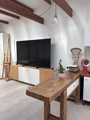 A room with a large flat-screen TV, wooden beams, a hanging light fixture, a vintage scale, and a small potted plant. - Holiday Home 'Loft Atelier Paris' with Shared Terrace, Wi-Fi and Air Conditioning (Montreuil)