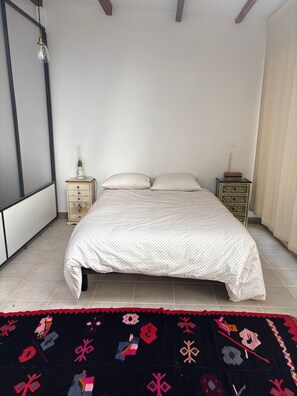 A bedroom with a bed, a nightstand, a lamp, and a patterned rug. - Holiday Home 'Loft Atelier Paris' with Shared Terrace, Wi-Fi and Air Conditioning (Montreuil)