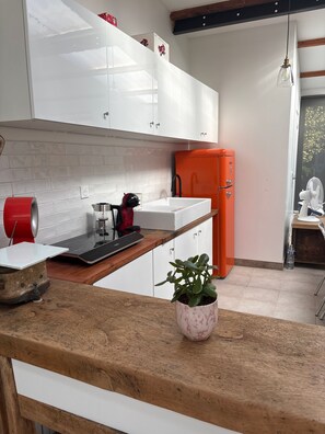 A kitchen with white cabinets, a red appliance, and a potted plant on the counter. - Holiday Home 'Loft Atelier Paris' with Shared Terrace, Wi-Fi and Air Conditioning (Montreuil)