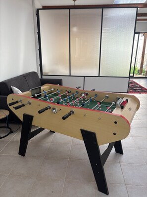 A foosball table in a room with a sofa and a large window. - Holiday Home 'Loft Atelier Paris' with Shared Terrace, Wi-Fi and Air Conditioning (Montreuil)