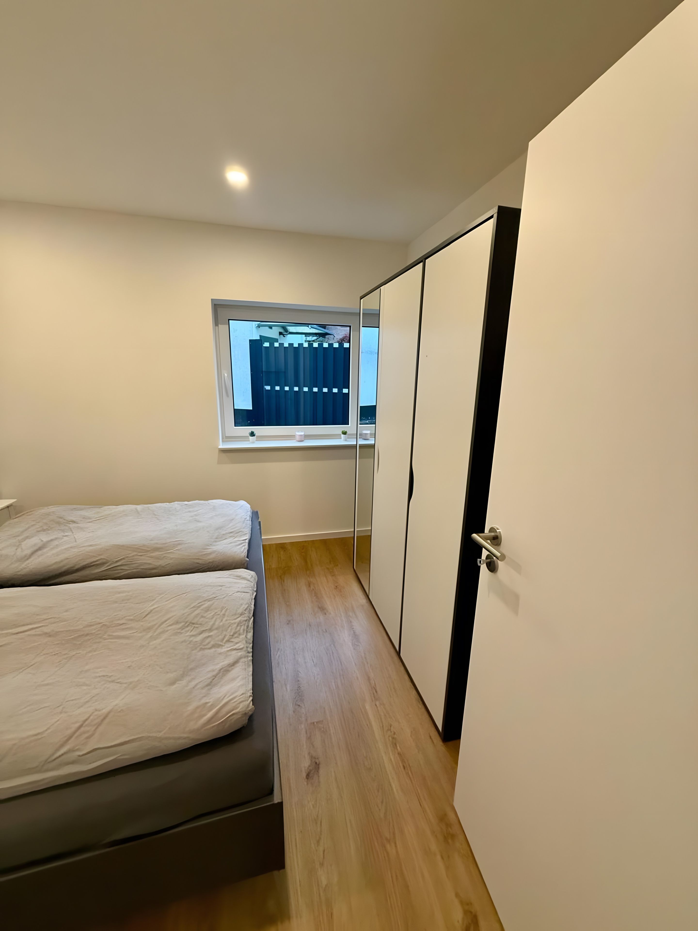 A bedroom with a bed, a window, and a wardrobe.