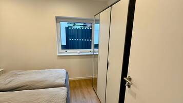 A bedroom with a bed, a window, and a wardrobe.