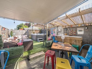Ein Außenbereich mit Terrasse, Whirlpool, Sitzgelegenheiten und einer Bar.