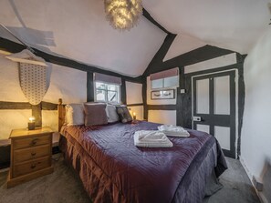 Ein Schlafzimmer mit einem großen Bett, einem Nachttisch, einer Lampe und einer Tür.