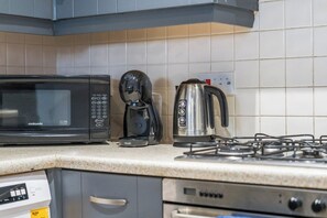 A kitchen with a microwave, coffee maker, kettle, and gas stove. - Artist Abode in York (York)