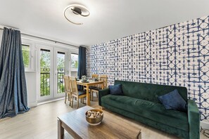 A living room with a green sofa, a wooden coffee table, and a patterned wall. - Stylish 2-Bedroom Retreat in Southampton (Southampton)