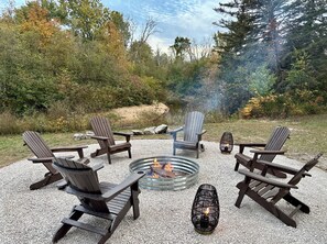 A circular seating arrangement with Adirondack chairs around a fire pit.