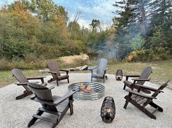 A circular seating arrangement with Adirondack chairs around a fire pit.