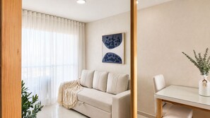 A modern living room with a sofa, a dining table, and a potted plant. - Ocean View and Comfort for Your Stay (Bolívar)