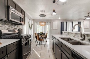 A modern kitchen with a central island, stainless steel appliances, and a dining area with a chandelier. - Peaceful & Spacious 4-bedroom house 20min Airport,FortSam & Downtown San Antonio (San Antonio)