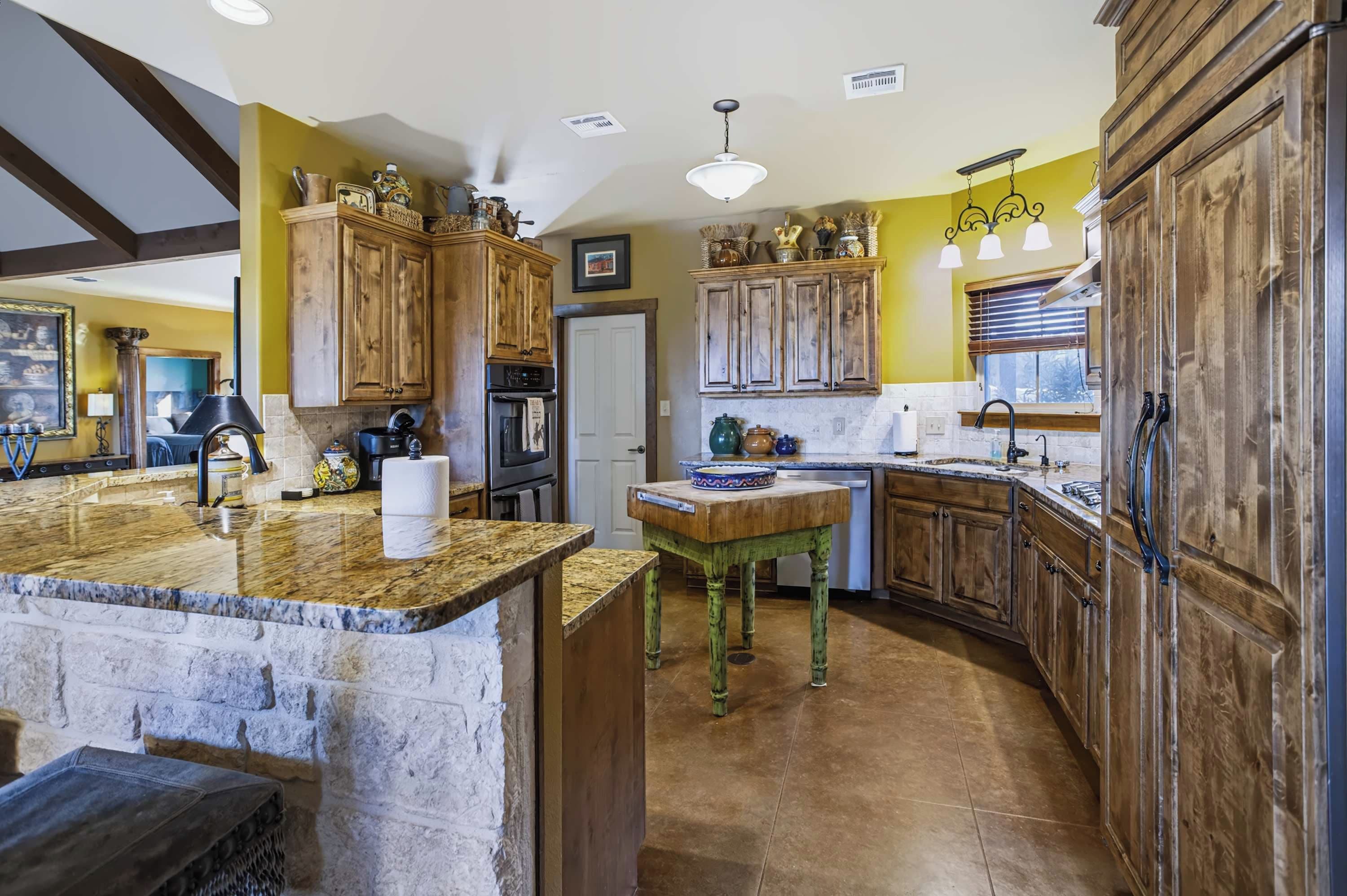 A kitchen with wooden cabinets, a granite countertop, and a stone island.