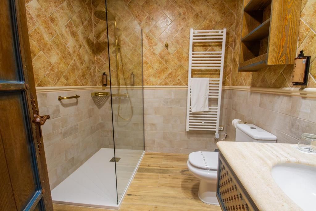 Casa de banho com cabine de chuveiro em vidro, sanita branca e lavatório de mármore.
