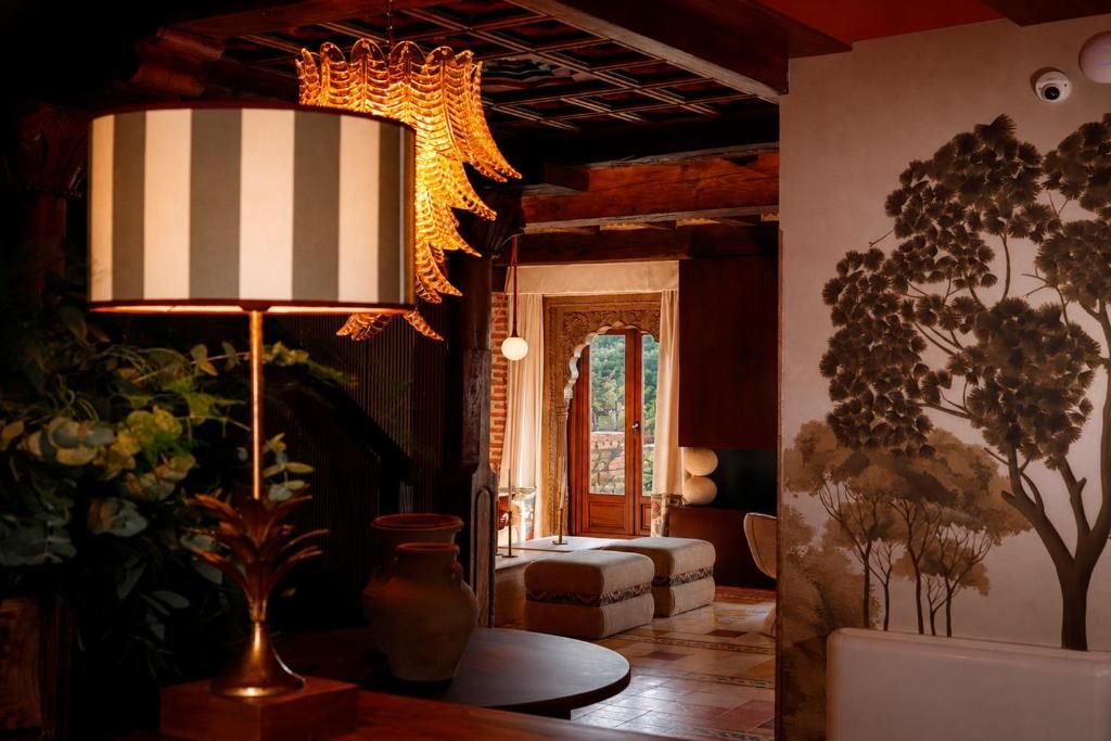 A room with a large striped lamp, a vase, and a wall mural of trees.