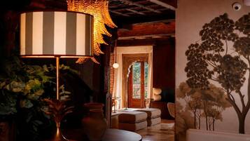 A room with a large striped lamp, a vase, and a wall mural of trees.