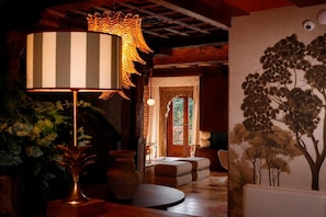 A room with a large striped lamp, a vase, and a wall mural of trees.