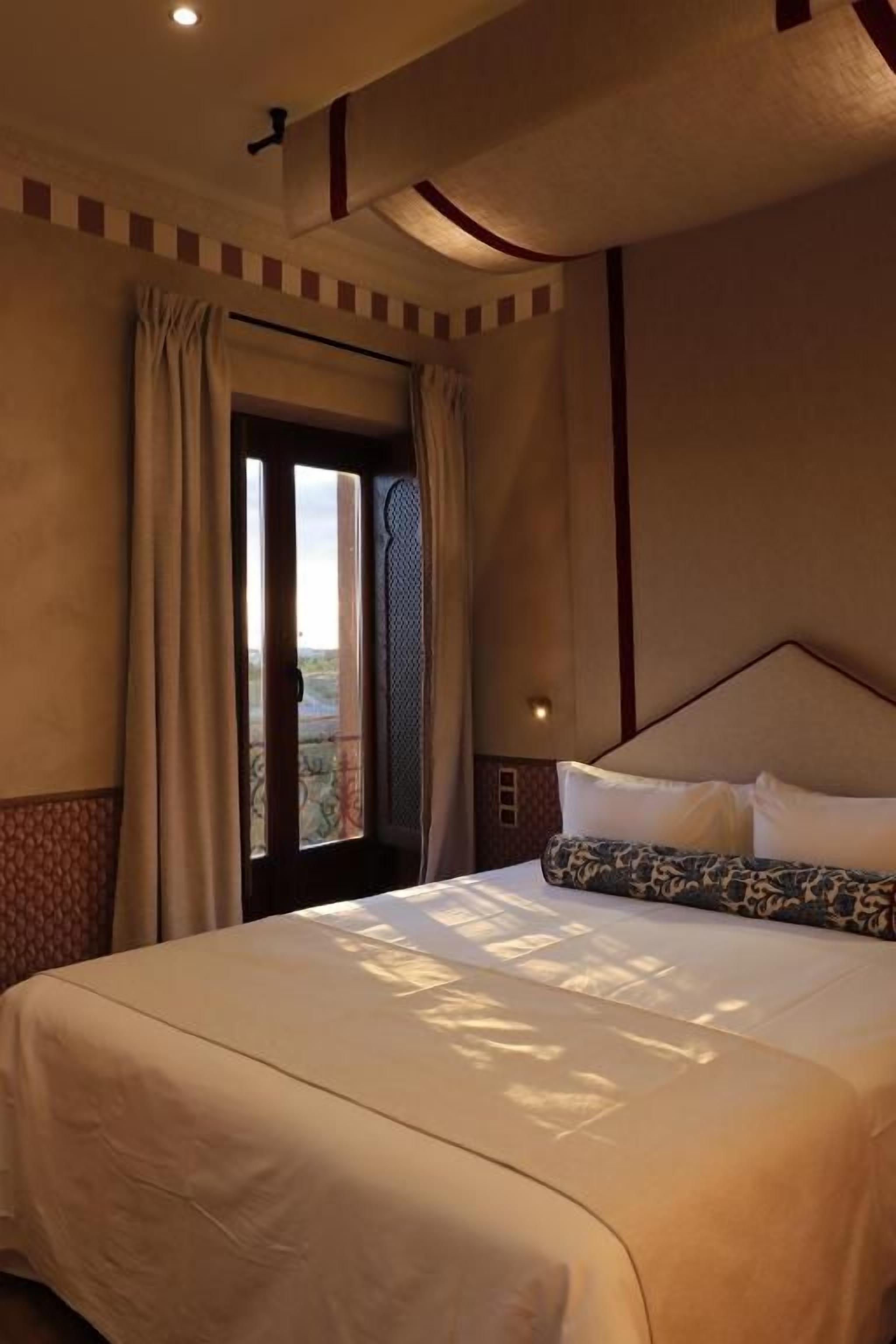 A hotel room with a large bed, a window with curtains, and a view of the outdoors.