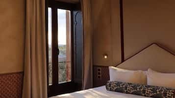 A hotel room with a large bed, a window with curtains, and a view of the outdoors.